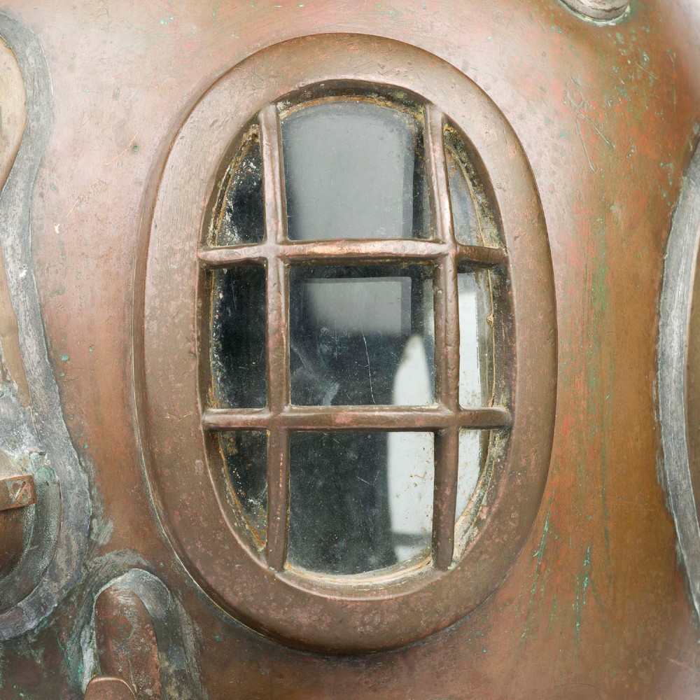 An antique Siebe Gorman copper and brass deep-sea diving helmet with a central circular viewport and lateral window grilles. View X