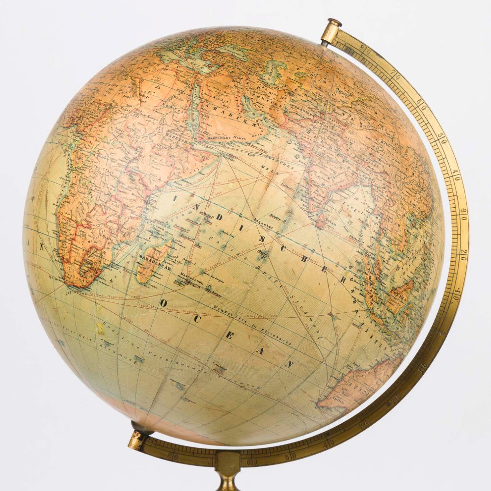 An antique terrestrial globe featuring paper printed maps mounted on a brass half-meridian ring and supported by a cast brass baluster stem base. View X