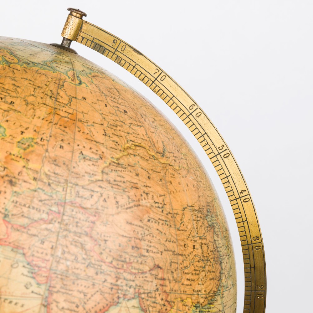 An antique terrestrial globe featuring paper printed maps mounted on a brass half-meridian ring and supported by a cast brass baluster stem base. View XI