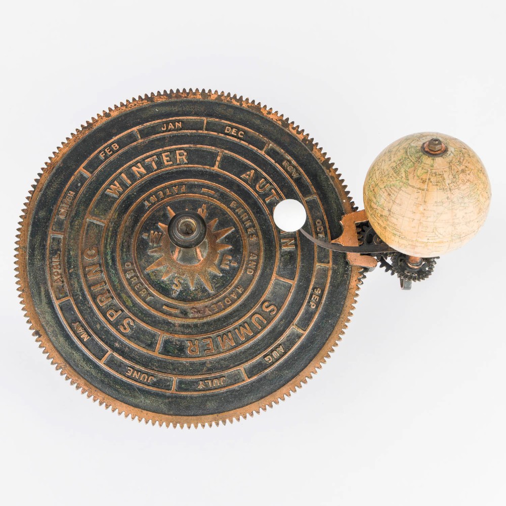 A Victorian Parkes and Hadley patent tellurian orrery featuring a cast metal base with calendar markings, interlocking gears, and a small terrestrial globe with a moon attachment. View VII
