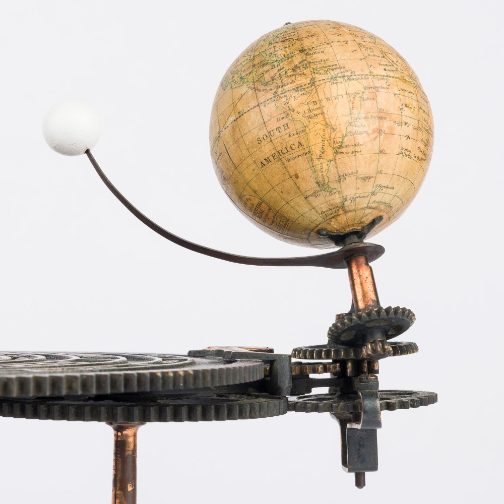 A Victorian Parkes and Hadley patent tellurian orrery featuring a cast metal base with calendar markings, interlocking gears, and a small terrestrial globe with a moon attachment. View IX