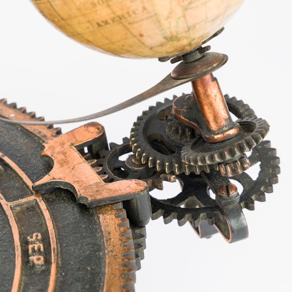 A Victorian Parkes and Hadley patent tellurian orrery featuring a cast metal base with calendar markings, interlocking gears, and a small terrestrial globe with a moon attachment. View XI