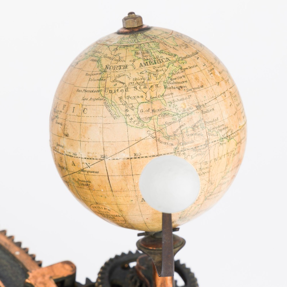 A Victorian Parkes and Hadley patent tellurian orrery featuring a cast metal base with calendar markings, interlocking gears, and a small terrestrial globe with a moon attachment. View XII