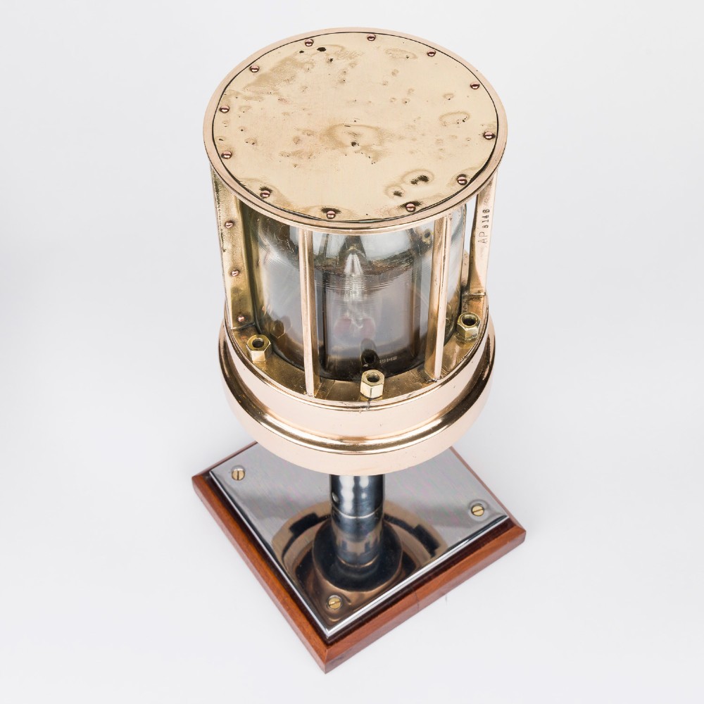A polished brass submarine steaming light featuring a clear glass dome encased in a protective metal cage, mounted on a chrome stem and wooden plinth. View III
