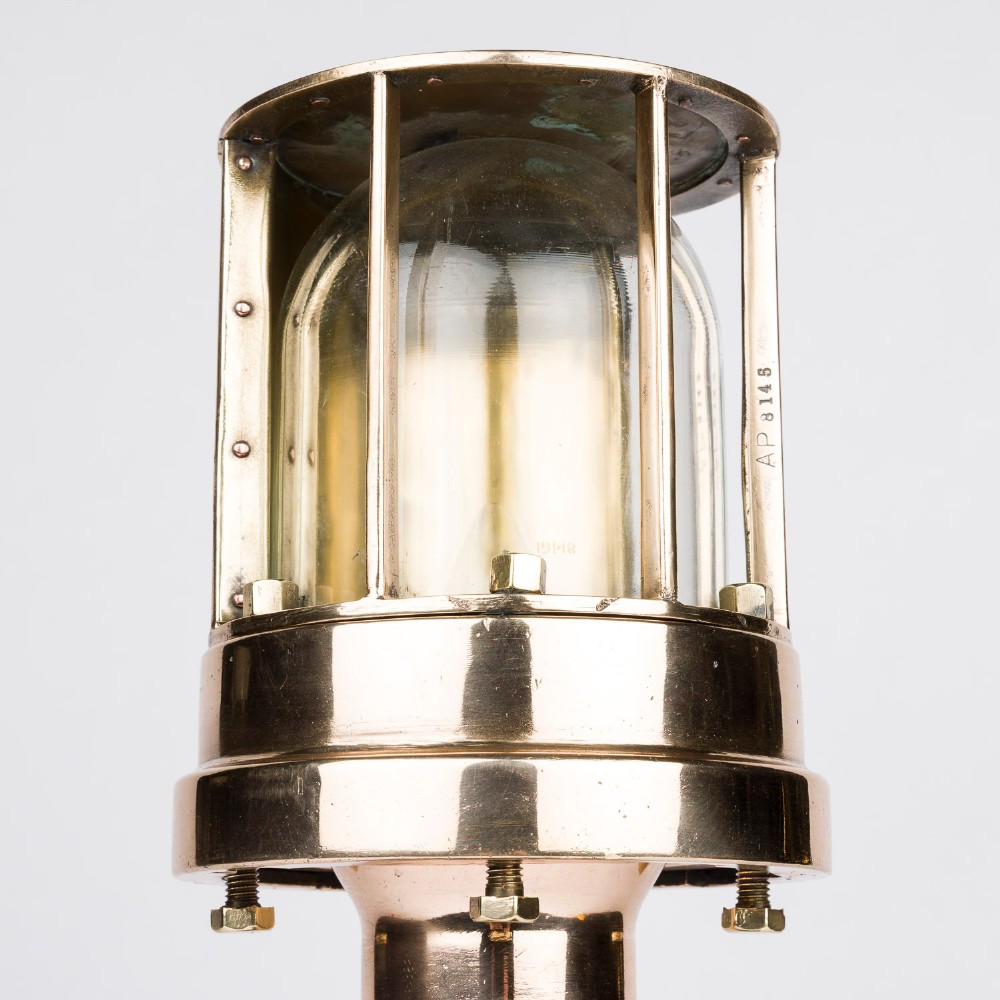 A polished brass submarine steaming light featuring a clear glass dome encased in a protective metal cage, mounted on a chrome stem and wooden plinth. View IV