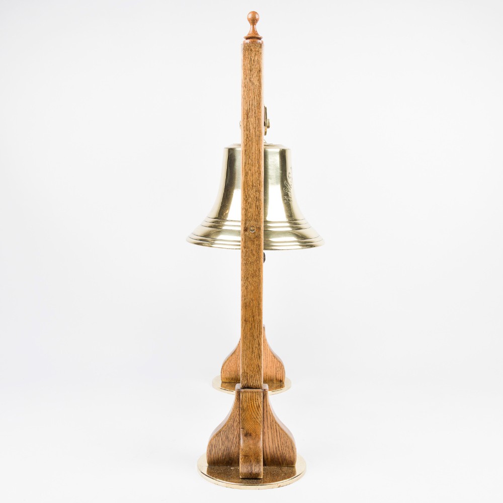 A polished brass Royal Navy ships bell engraved HMS Roysterer 1919, suspended inside a light oak wooden frame. View V