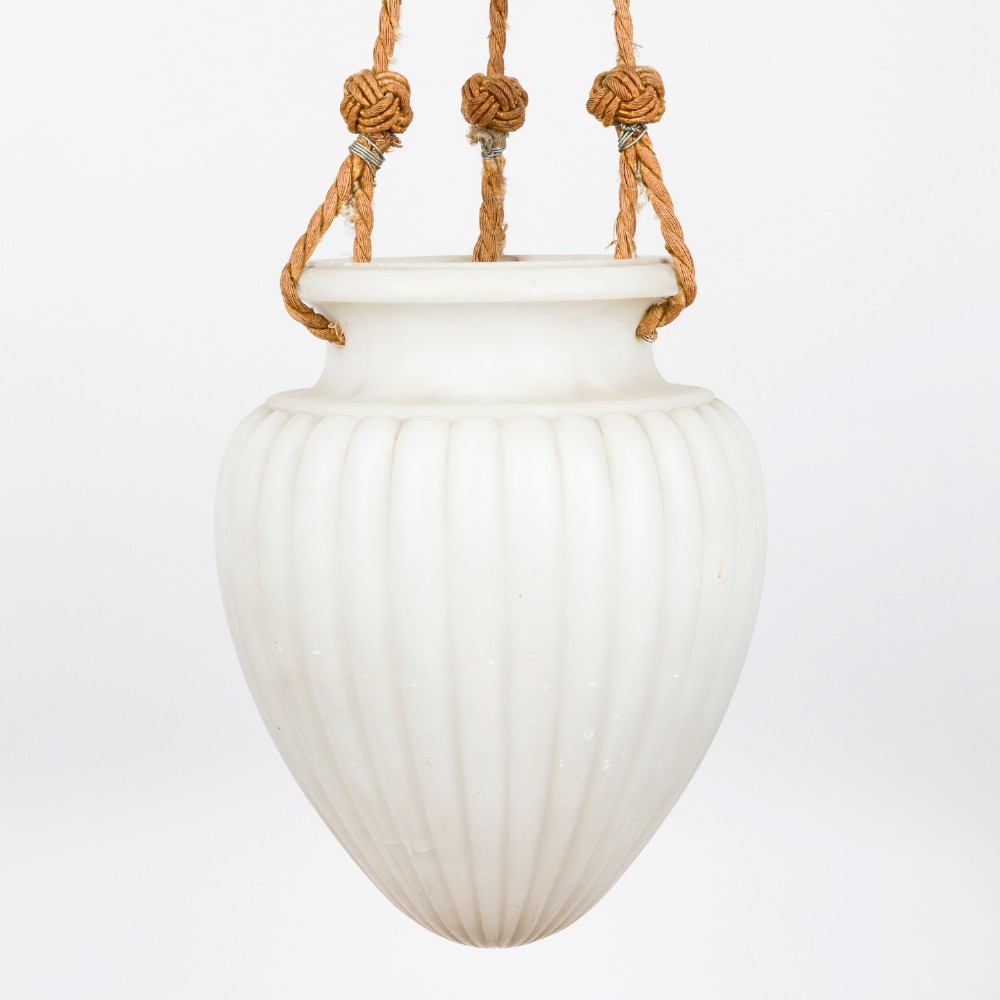 A fluted white alabaster urn-shaped light shade suspended by decorative woven cords and tassels from a matching alabaster ceiling rose. View II