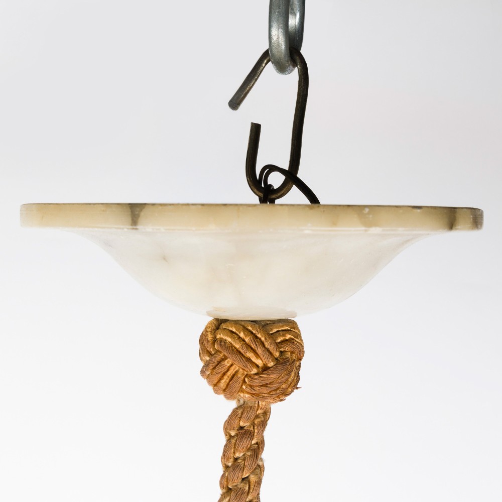 A fluted white alabaster urn-shaped light shade suspended by decorative woven cords and tassels from a matching alabaster ceiling rose. View V
