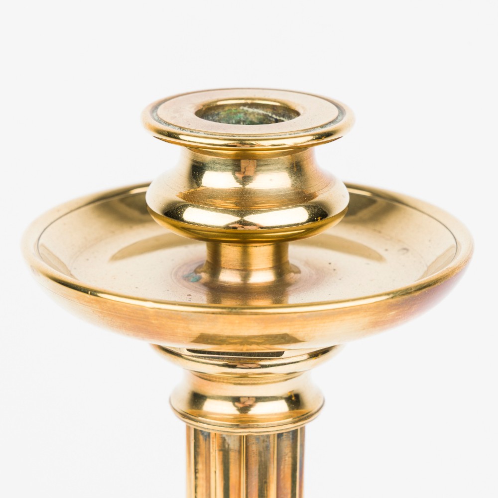 A pair of polished bronze Art Deco candlesticks featuring fluted vertical columns and stepped square plinth bases. View V