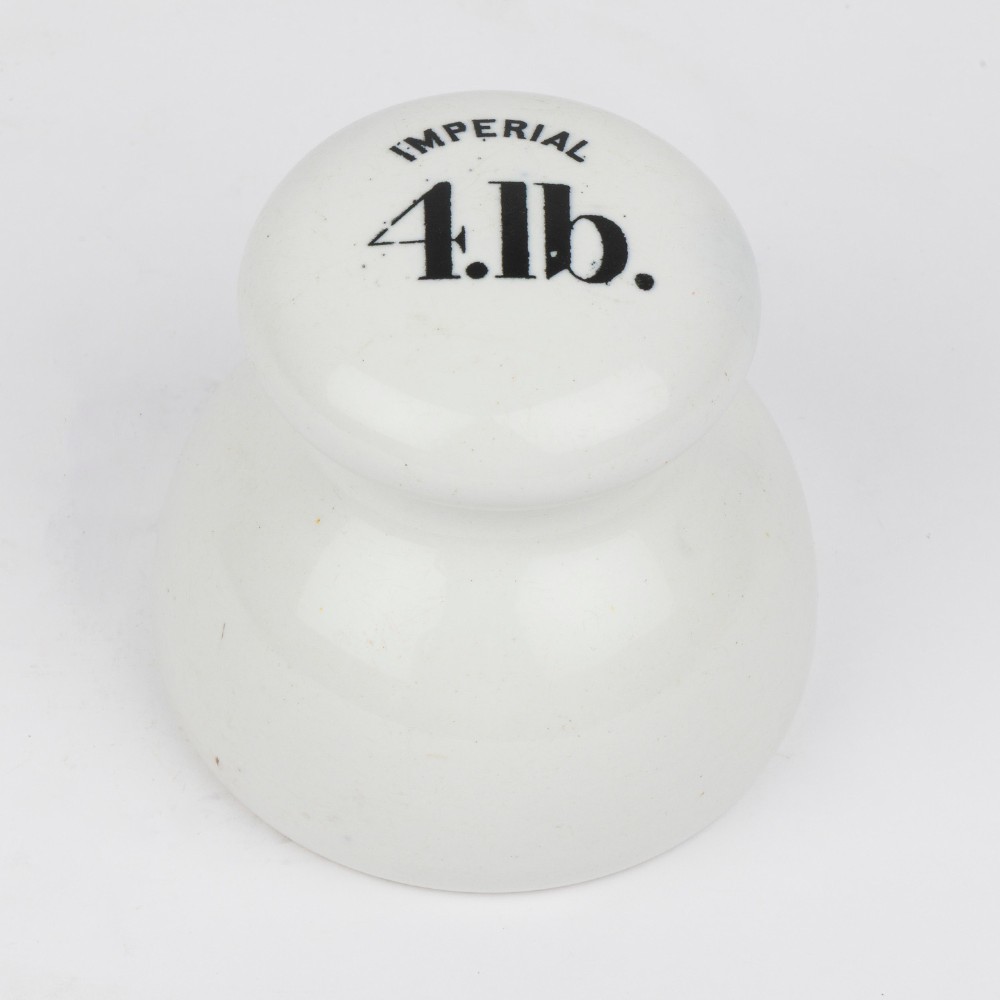 A white glazed ceramic four pound scale weight with black lettering reading Imperial 4 lb printed on top.