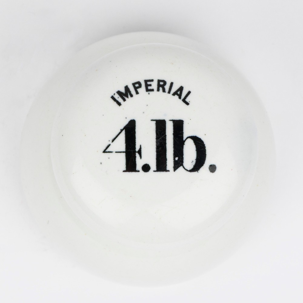 A white glazed ceramic four pound scale weight with black lettering reading Imperial 4 lb printed on top. View II