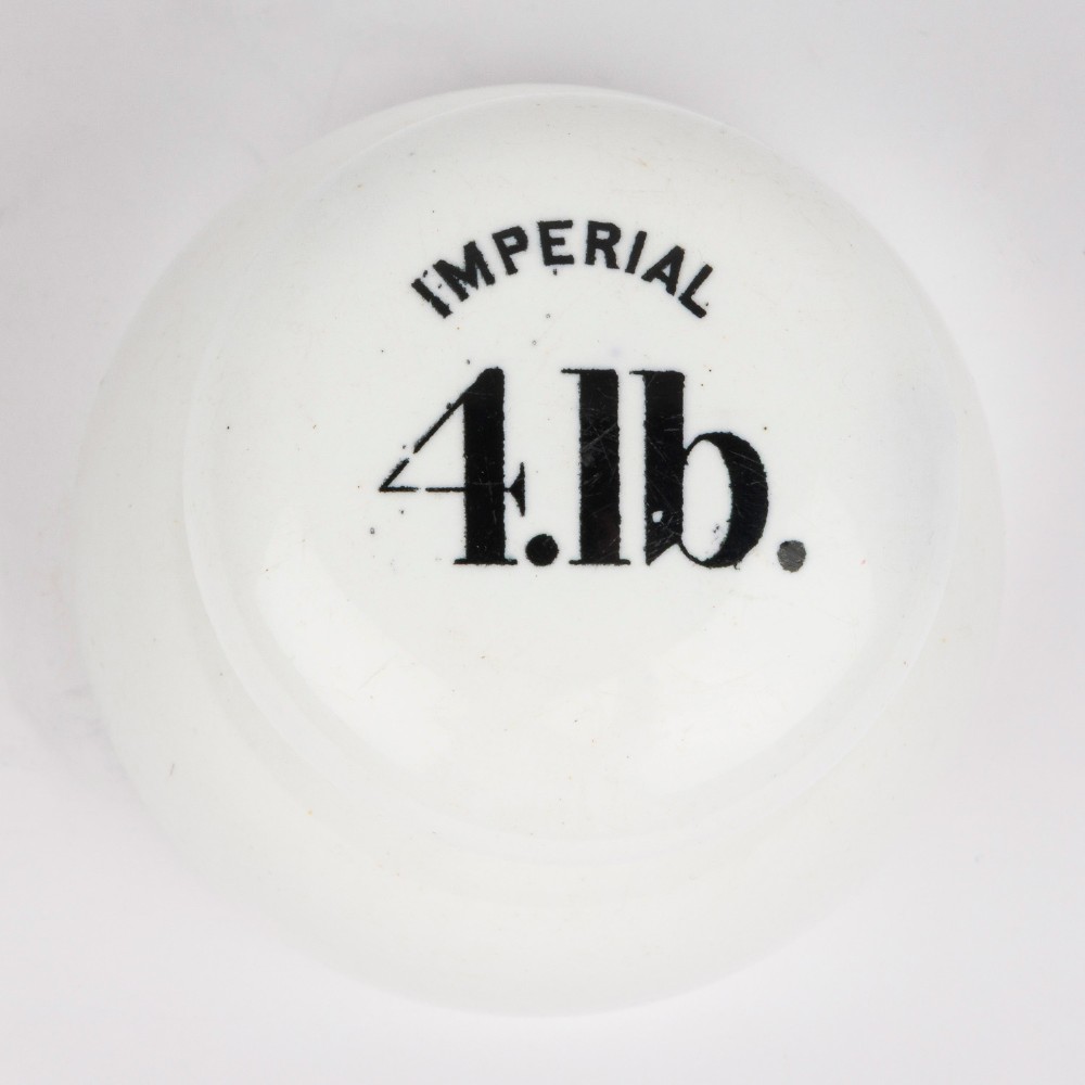 A white glazed ceramic four pound scale weight with black lettering reading Imperial 4 lb printed on top. View VI