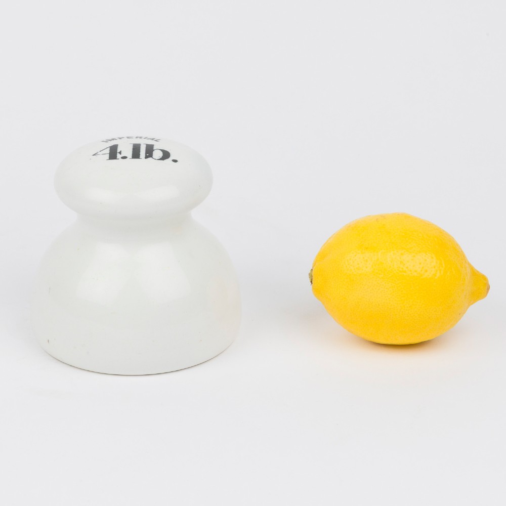 A white glazed ceramic four pound scale weight with black lettering reading Imperial 4 lb printed on top. View VIII