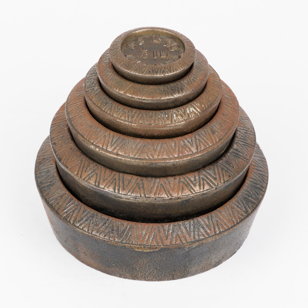 A set of six graduated cast iron nested imperial scale weights stacked into a pyramid shape, featuring textured chevron banding along the sides.