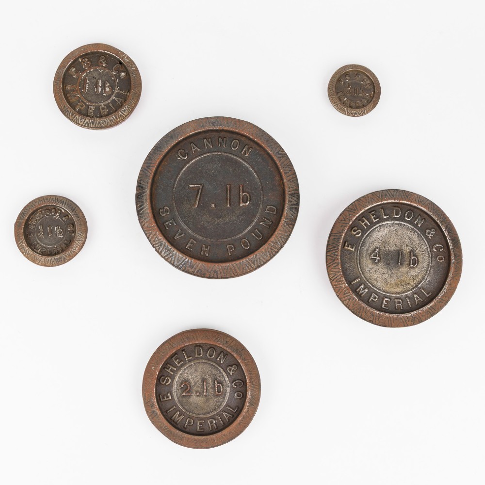 A set of six graduated cast iron nested imperial scale weights stacked into a pyramid shape, featuring textured chevron banding along the sides. View III