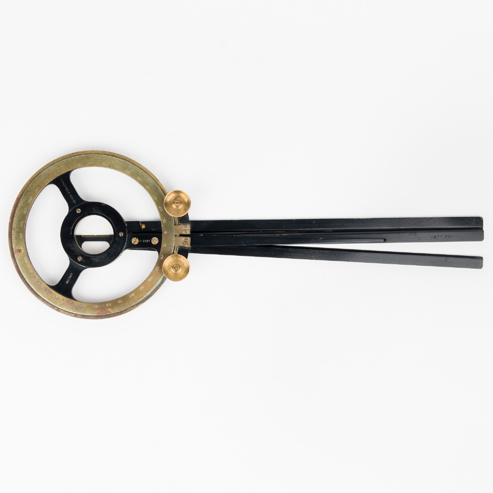 An antique brass and black lacquered three-arm station pointer with a circular graduated dial and precision adjustment knobs.