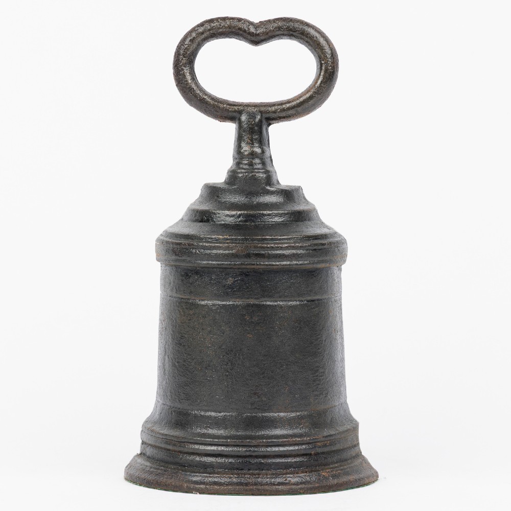 A Victorian cast iron door porter with a bell-shaped body and a heart-shaped loop handle at the top.