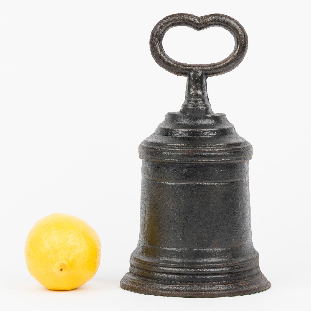 A Victorian cast iron door porter with a bell-shaped body and a heart-shaped loop handle at the top. View VII