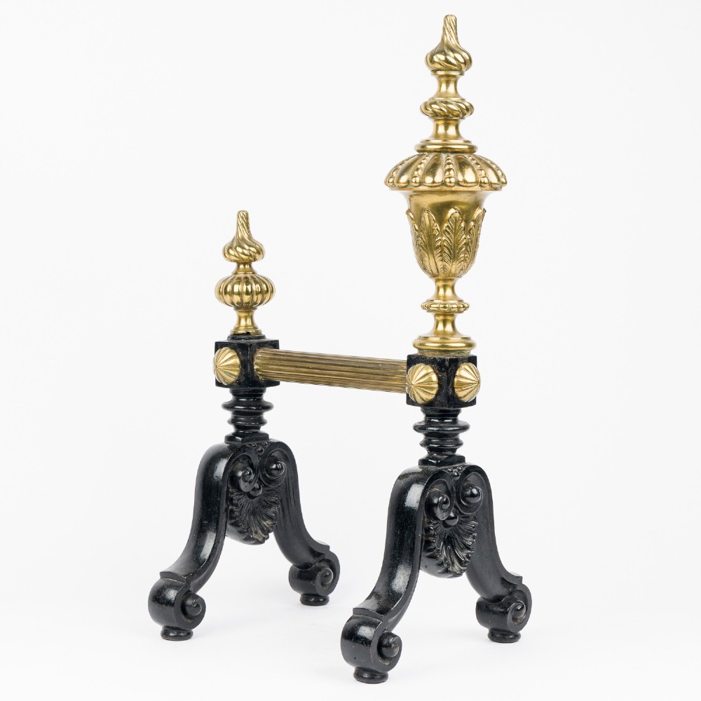 A pair of cast iron and brass fire dogs with ornate brass urn finials, fluted central bars, and black scroll feet. View IV