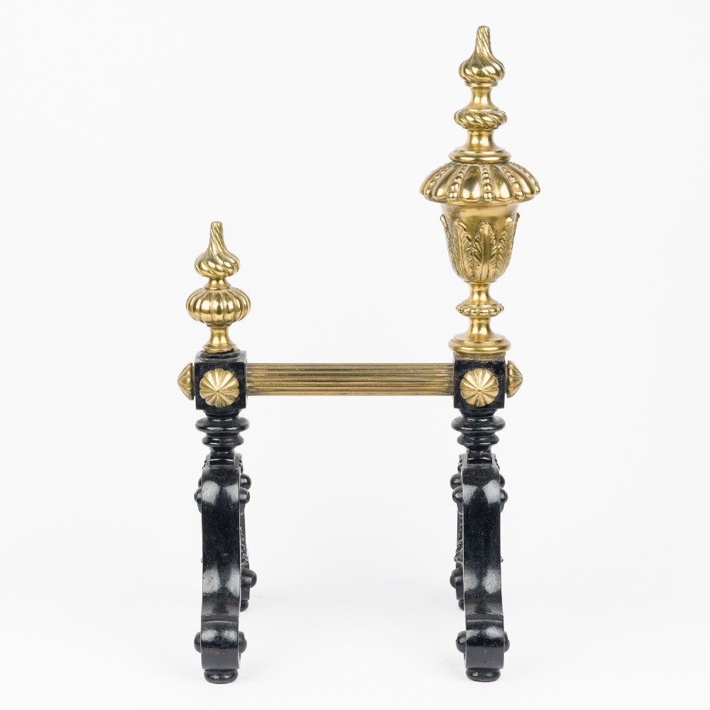 A pair of cast iron and brass fire dogs with ornate brass urn finials, fluted central bars, and black scroll feet. View VII