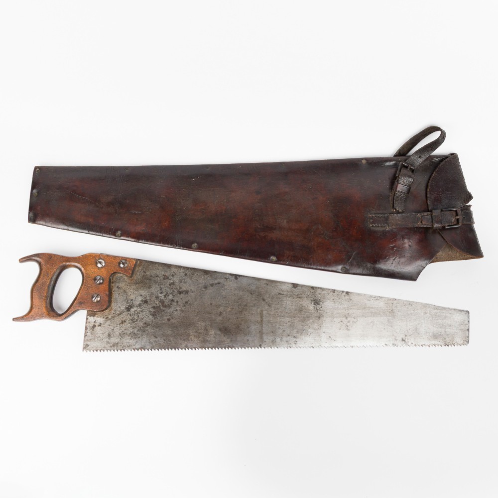 An antique steel hand saw featuring a patinated blade with visible teeth and a shaped wooden handle secured with metal rivets. View V