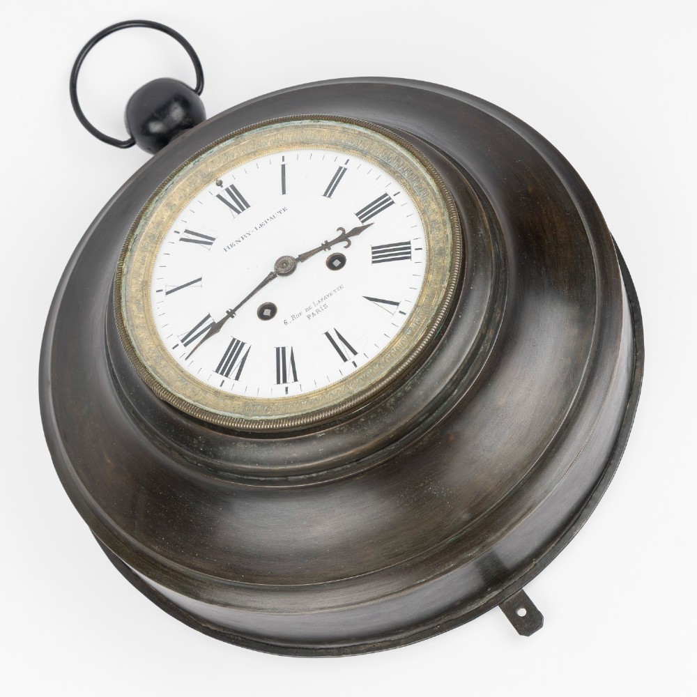 A circular dark bronze French wall clock designed in the shape of a pocket watch with a white enamel dial and Roman numerals. View III