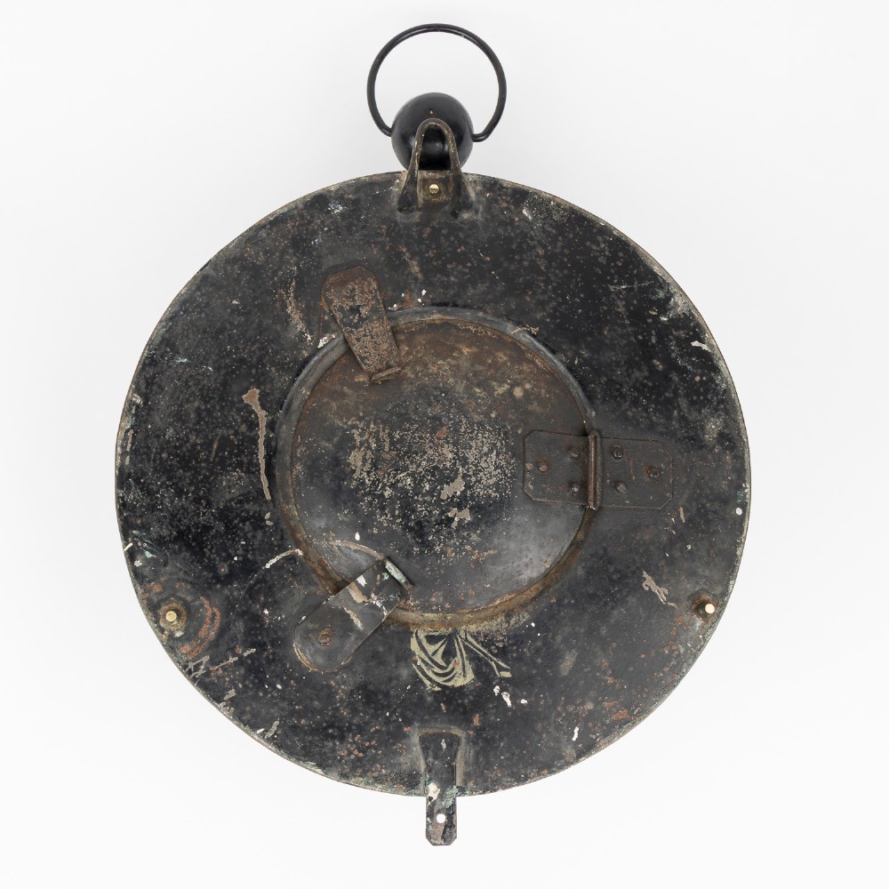 A circular dark bronze French wall clock designed in the shape of a pocket watch with a white enamel dial and Roman numerals. View VI