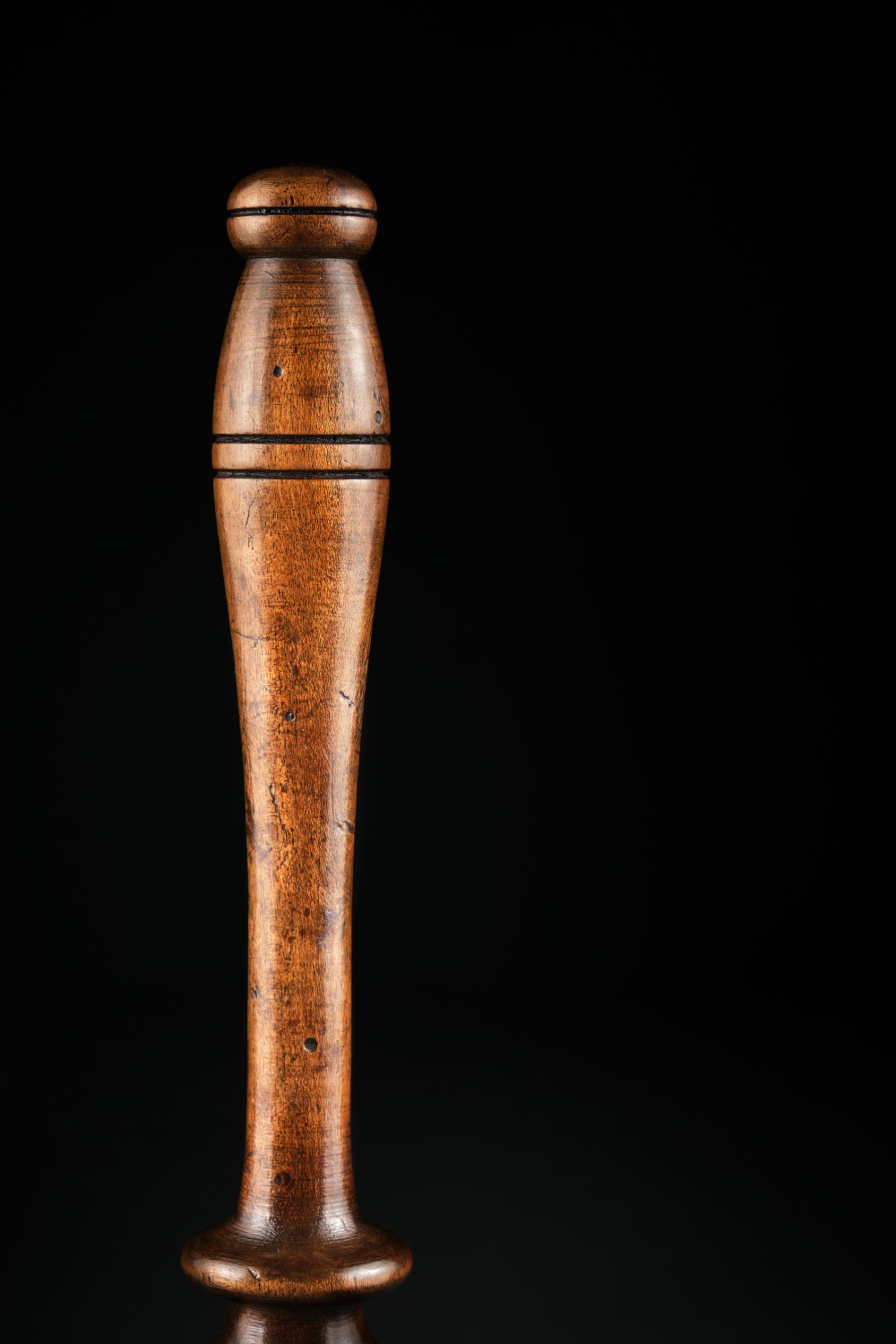 A turned dark brown sycamore wood potato masher featuring a contoured handle and bulbous head with visible age patina. View IV