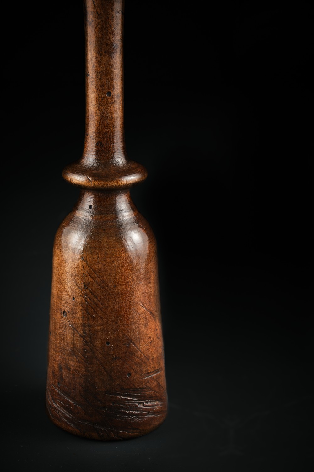 A turned dark brown sycamore wood potato masher featuring a contoured handle and bulbous head with visible age patina. View V