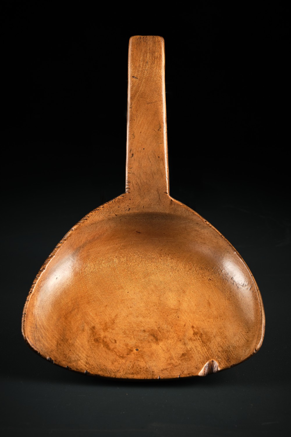 A hand-carved antique Welsh sycamore wooden scoop featuring a straight flat handle and a flared wide shallow bowl.