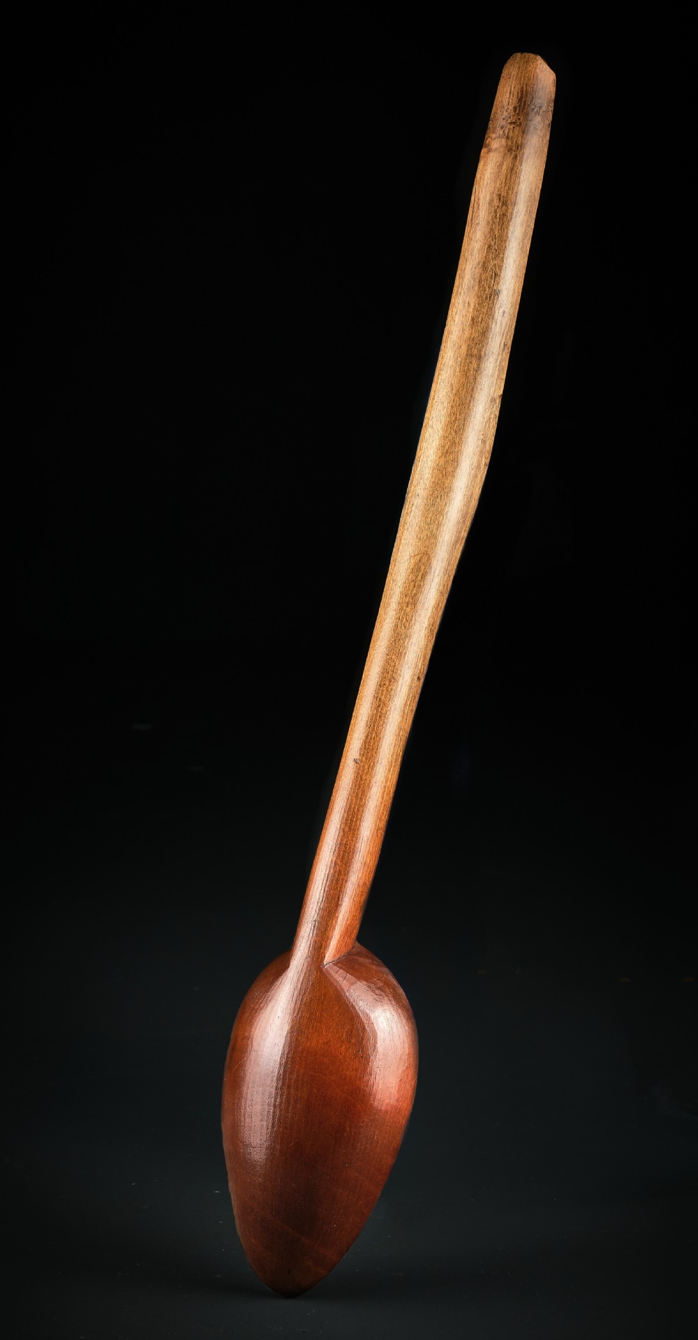 A long-handled Georgian beechwood basting spoon with a carved oval bowl against a black background. View III