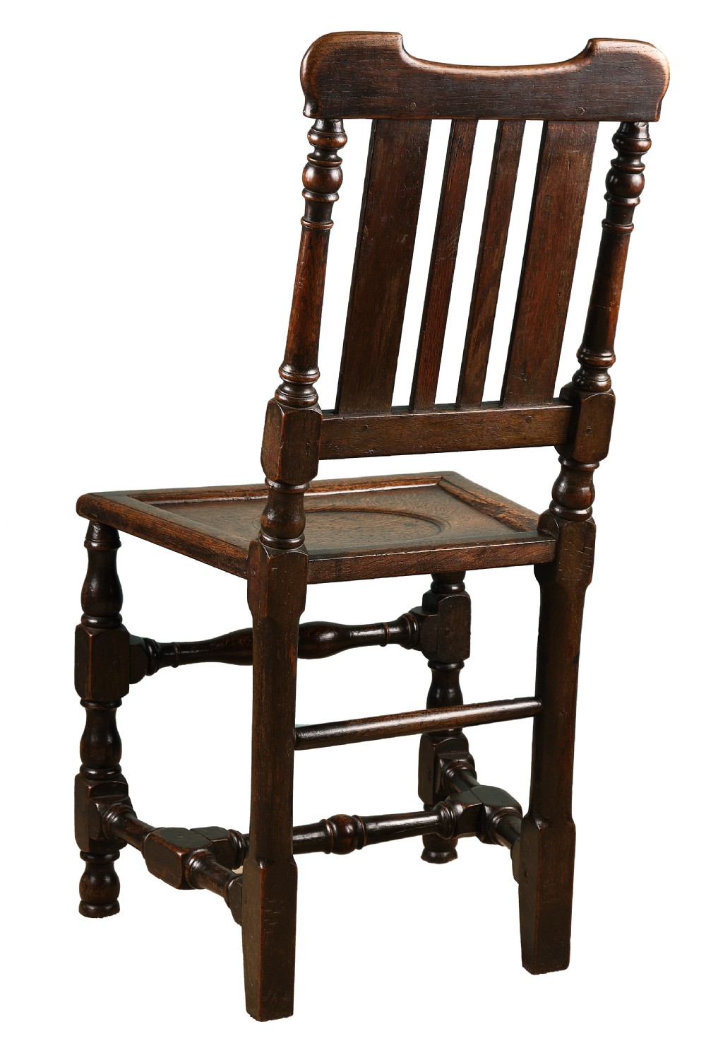 A late 17th-century dark oak side chair featuring turned legs, vertical back slats, and a carved crest rail. View II