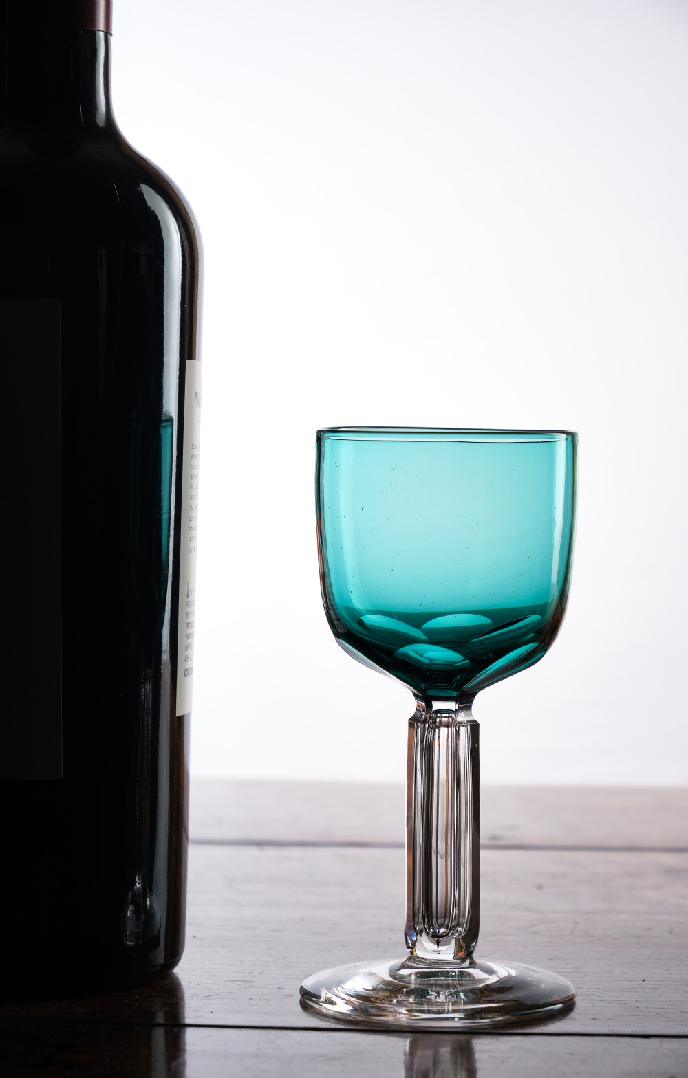 A Victorian teal glass stemware piece featuring a round coloured bowl and a clear faceted cut stem on a circular base. View III