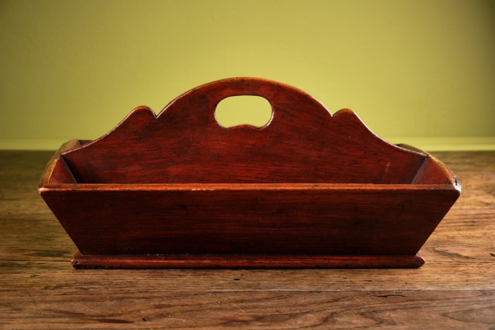 A red-painted wooden knife tray featuring a central divider with an integrated oval handle cut-out and shaped cresting. View II