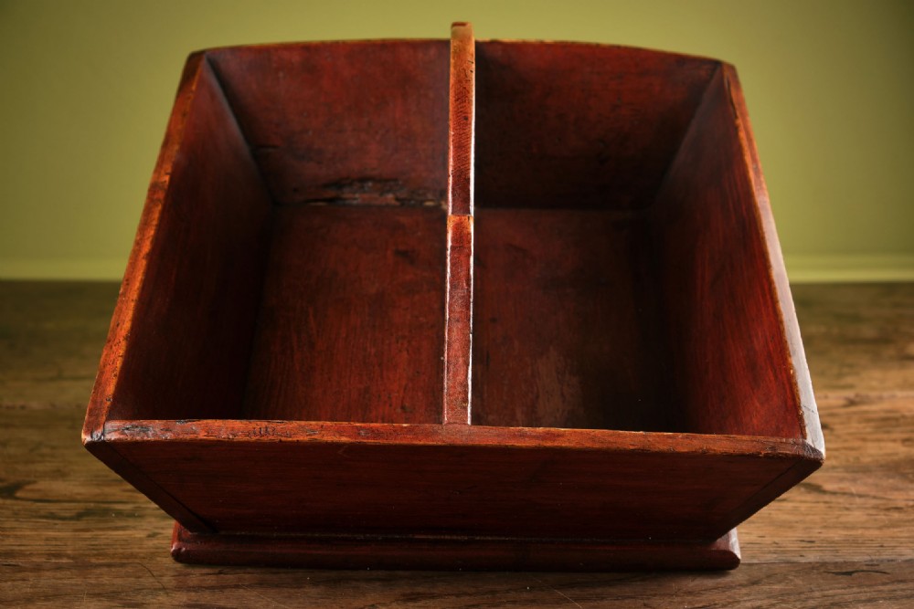 A red-painted wooden knife tray featuring a central divider with an integrated oval handle cut-out and shaped cresting. View III