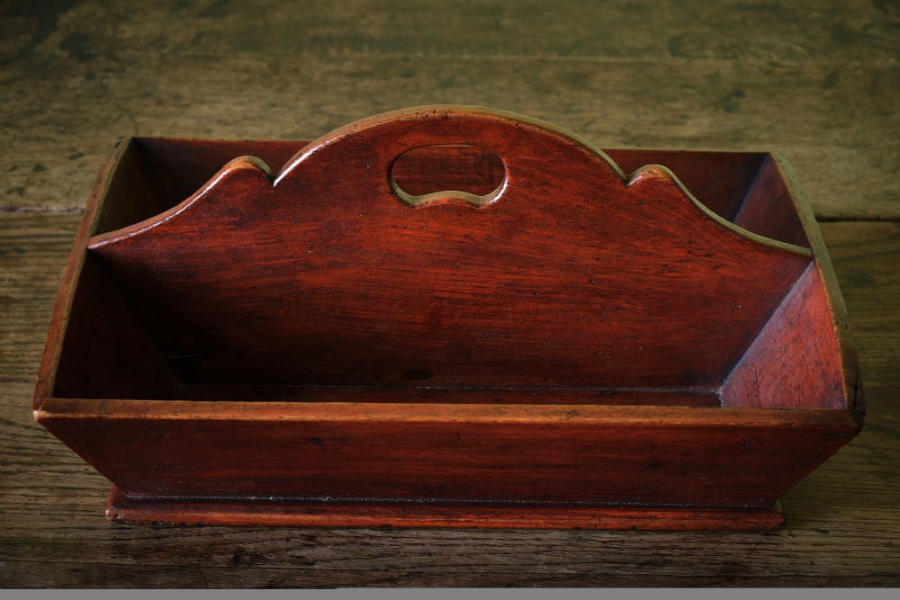 A red-painted wooden knife tray featuring a central divider with an integrated oval handle cut-out and shaped cresting. View IV