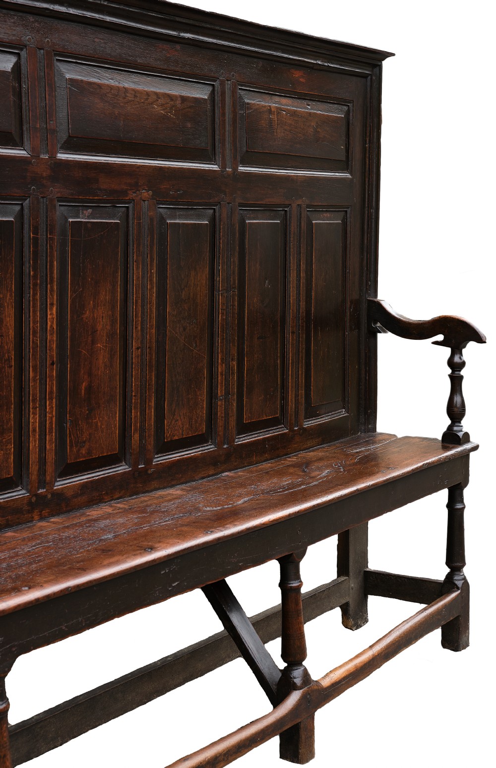 A high-backed dark oak settle with fielded panelling across the backrest, turned front legs, and a long wooden seat. View III