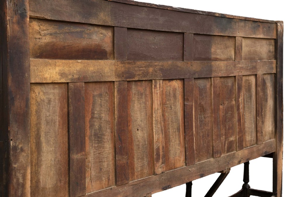 A high-backed dark oak settle with fielded panelling across the backrest, turned front legs, and a long wooden seat. View VI