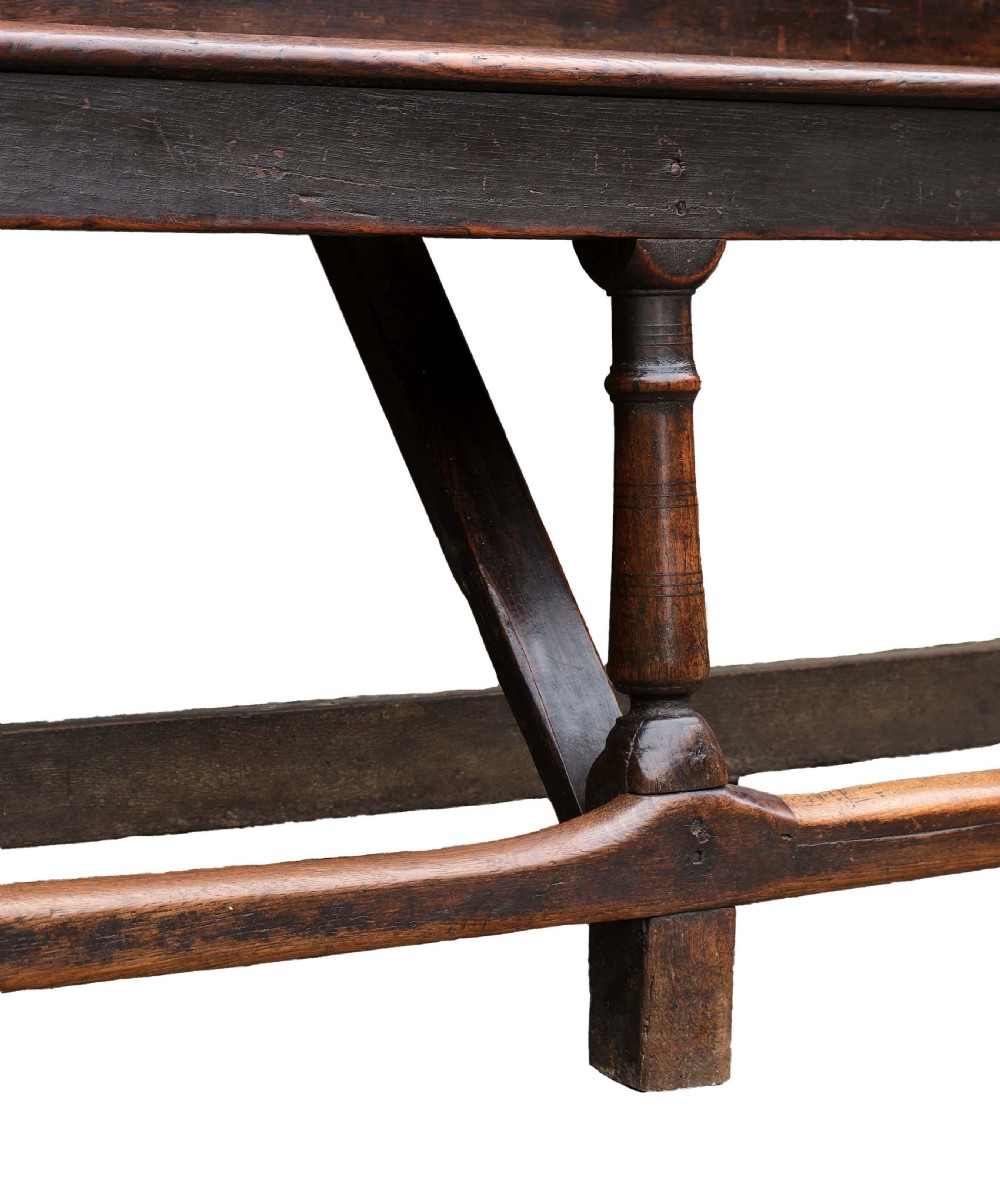 A high-backed dark oak settle with fielded panelling across the backrest, turned front legs, and a long wooden seat. View VIII