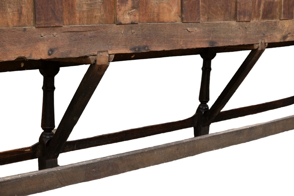 A high-backed dark oak settle with fielded panelling across the backrest, turned front legs, and a long wooden seat. View IX