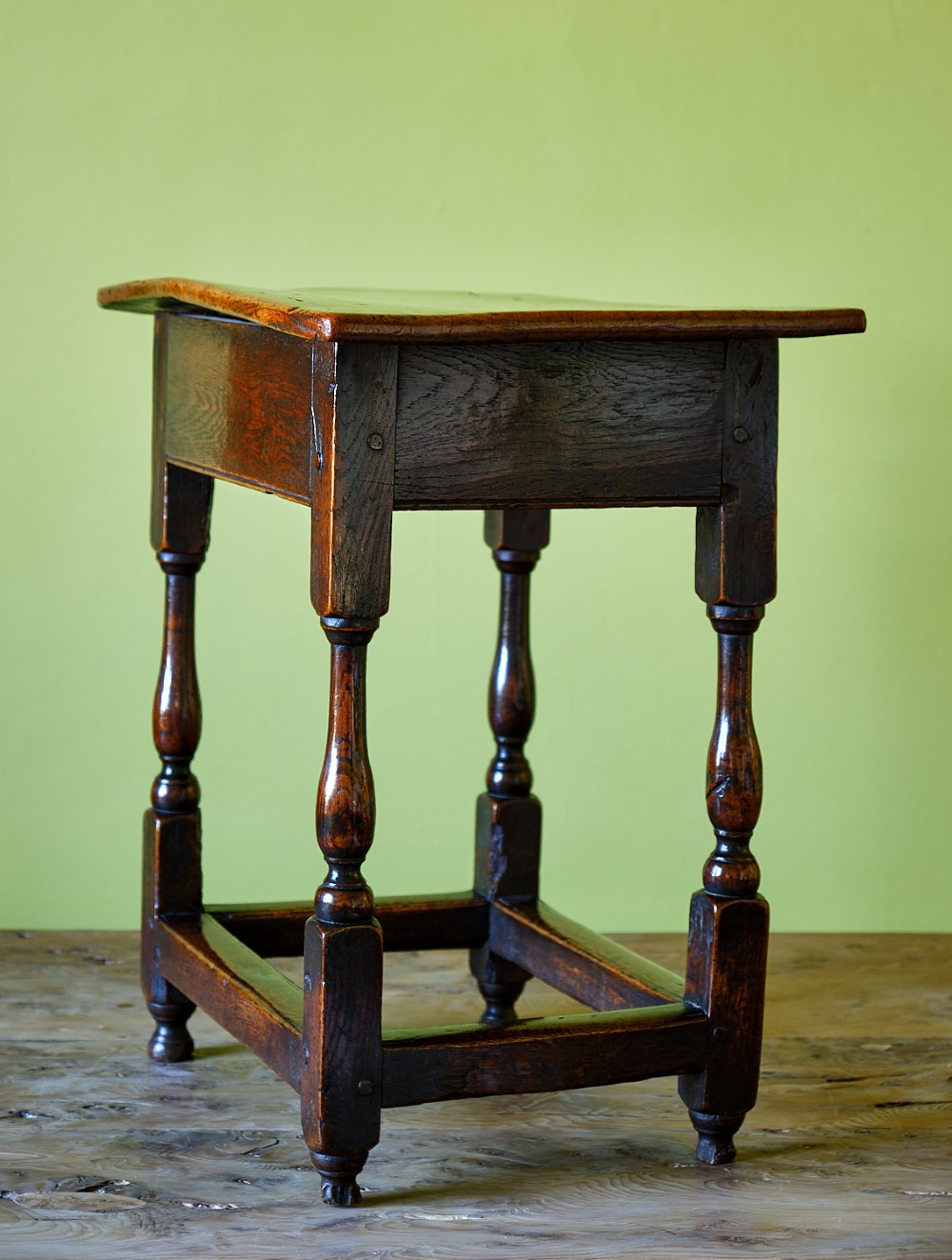 A small early 18th-century dark oak and elm occasional table featuring turned legs, a plank top, and lower stretchers. View II