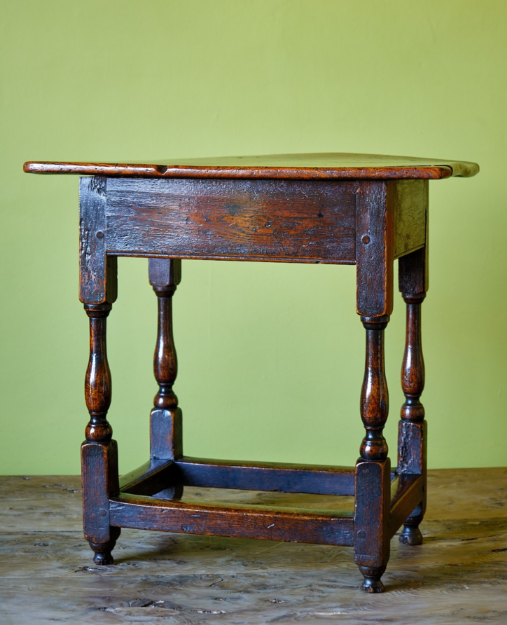 A small early 18th-century dark oak and elm occasional table featuring turned legs, a plank top, and lower stretchers. View III