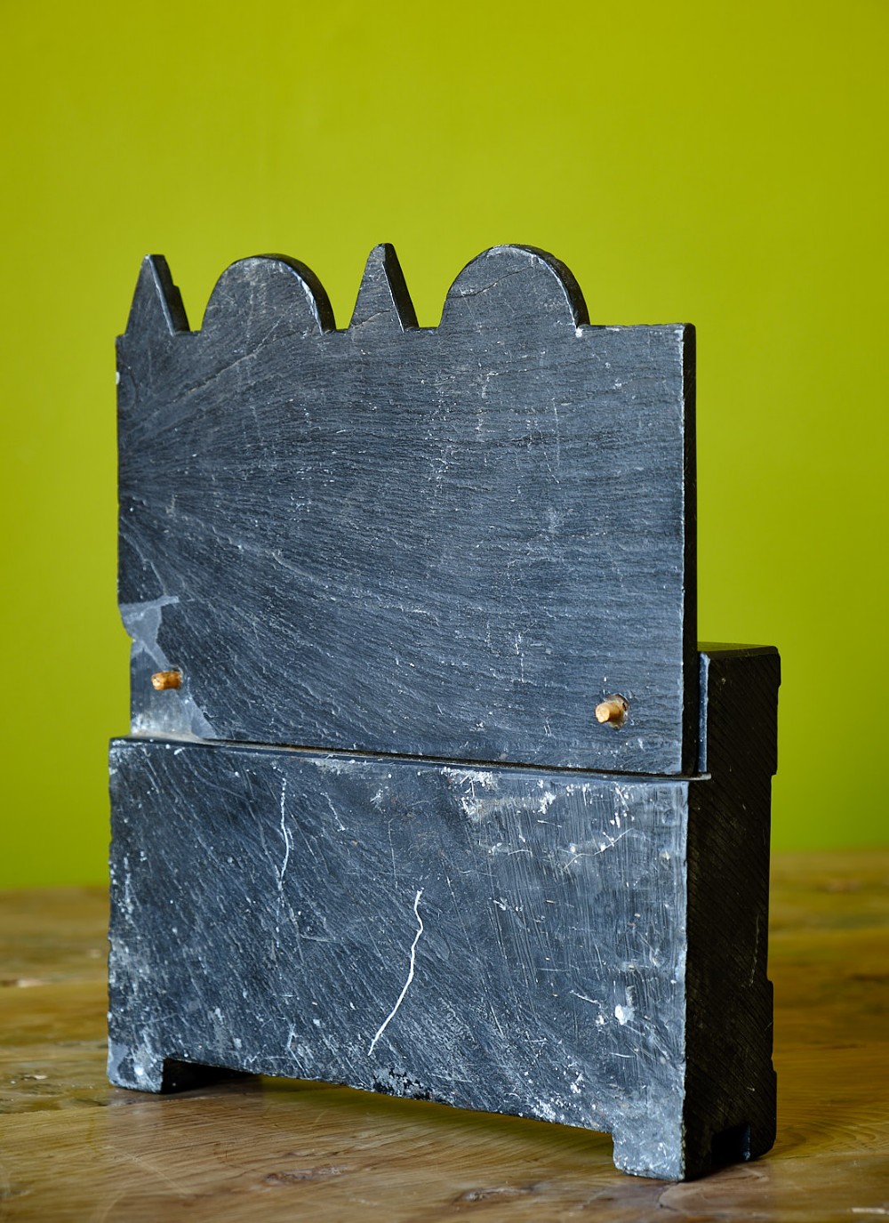 A miniature carved dark slate chest of drawers featuring geometric engravings, circular motifs, and small brass knobs. View III