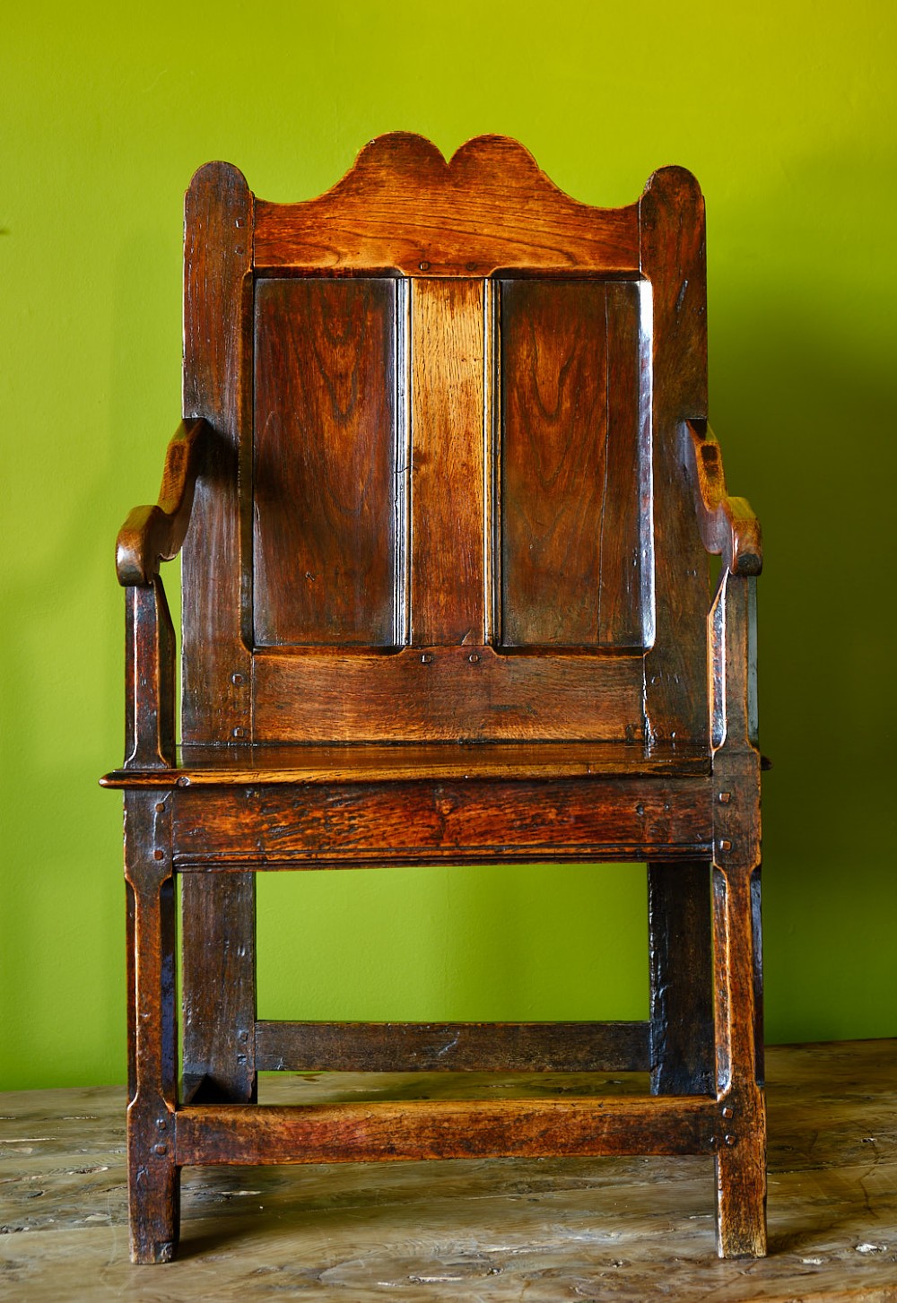 A late 17th-century dark oak armchair featuring a panelled backrest, shaped crest rail, curved armrests, rectangular wooden seat, and square legs with low stretchers. View II