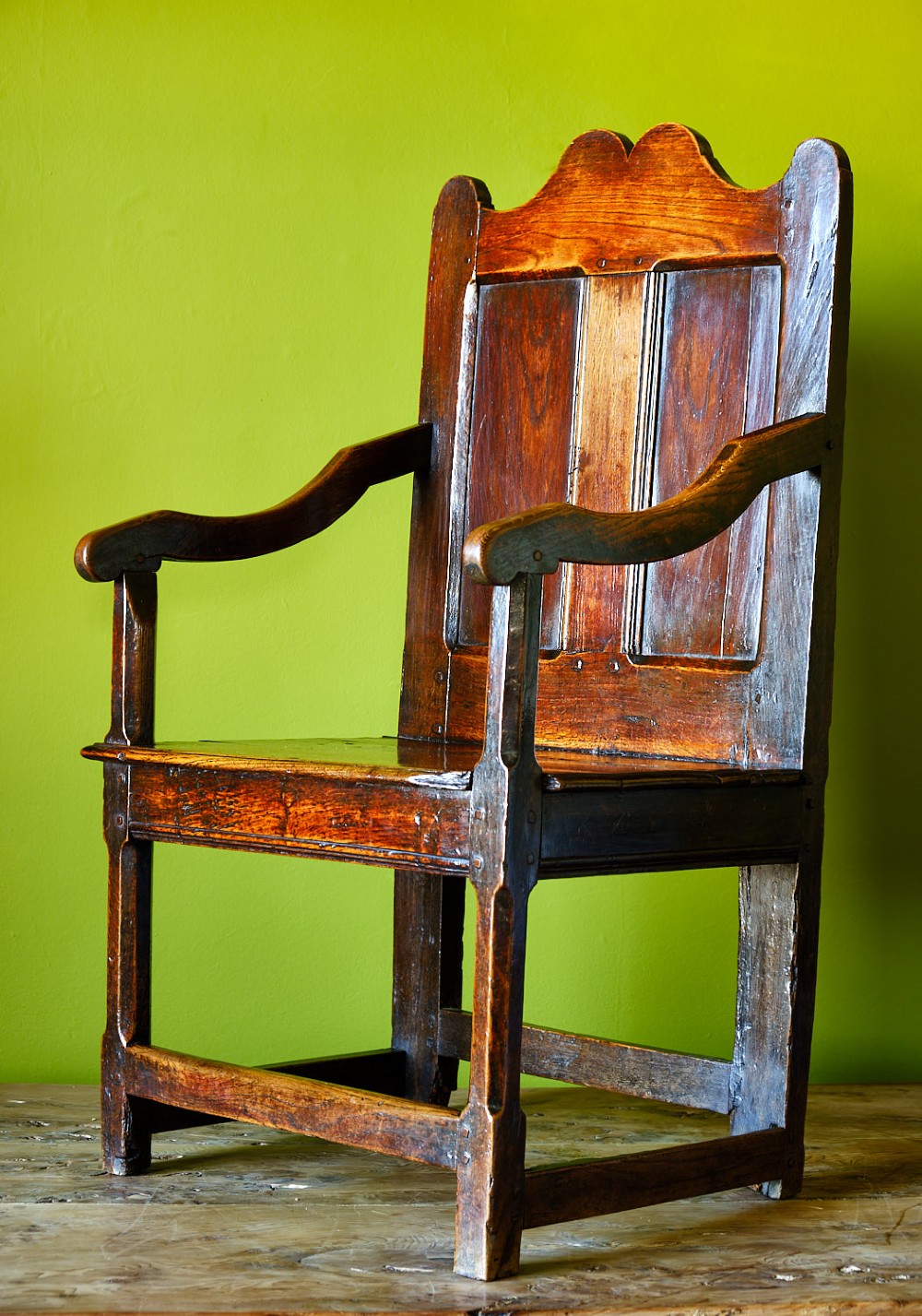 A late 17th-century dark oak armchair featuring a panelled backrest, shaped crest rail, curved armrests, rectangular wooden seat, and square legs with low stretchers. View III