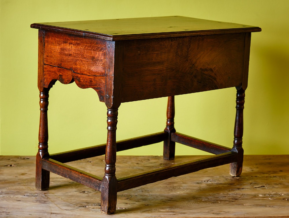 A Georgian oak side table featuring a single drawer with brass handles, a scalloped apron below, turned legs, and a perimeter stretcher. View IV