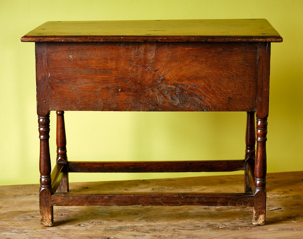 A Georgian oak side table featuring a single drawer with brass handles, a scalloped apron below, turned legs, and a perimeter stretcher. View V