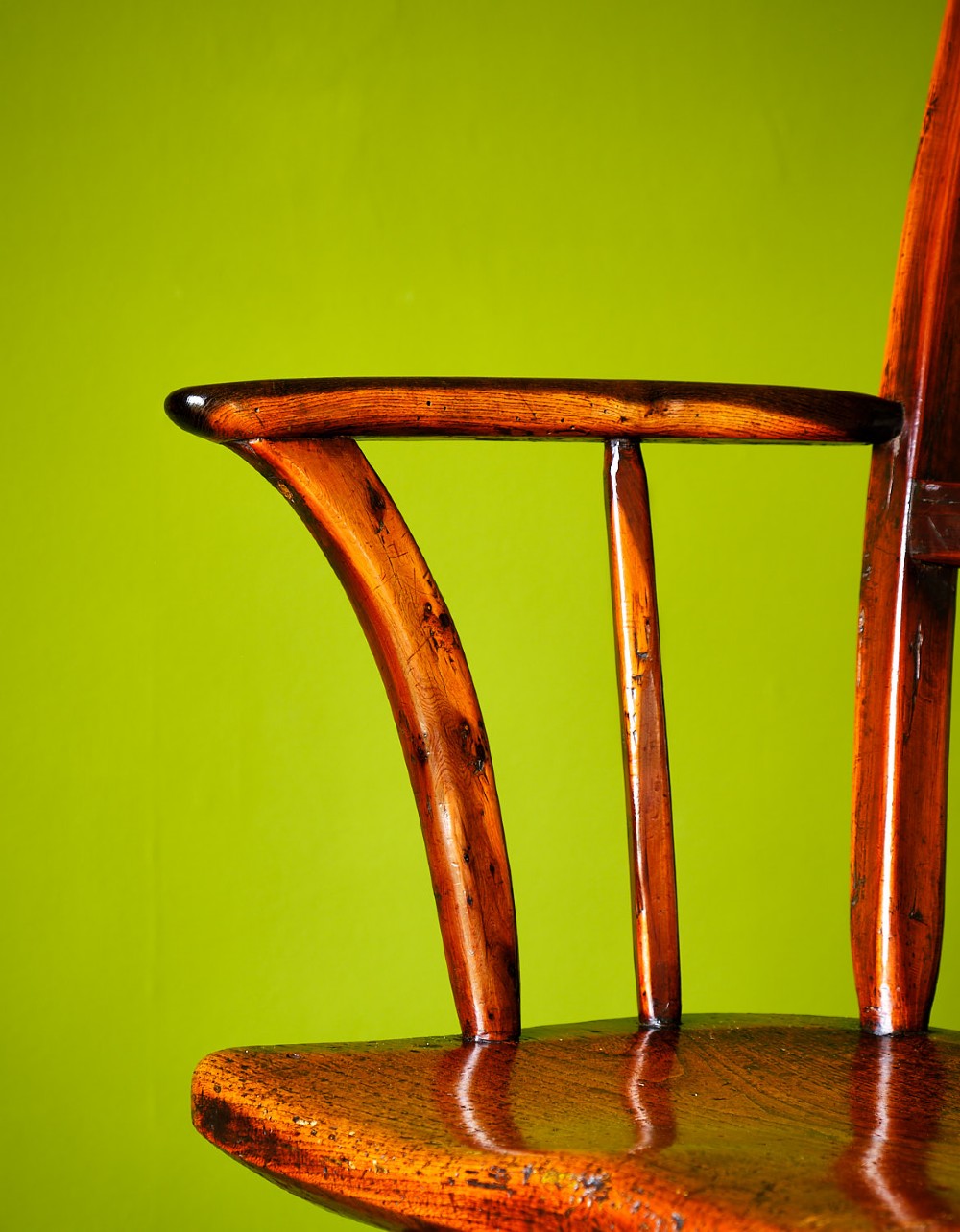 A primitive wooden Windsor armchair crafted from varied native hardwoods featuring a solid carved seat, shaped central back splat, tapered spindles, and splayed legs. View VII
