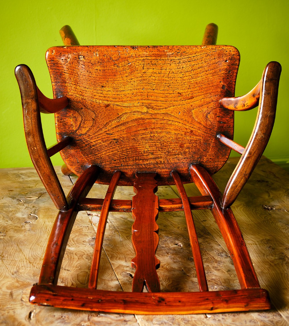 A primitive wooden Windsor armchair crafted from varied native hardwoods featuring a solid carved seat, shaped central back splat, tapered spindles, and splayed legs. View IX