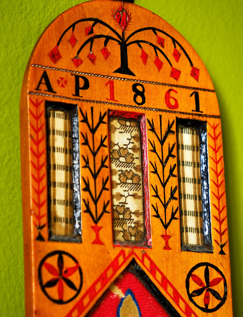 A carved wooden Welsh love spoon featuring polychrome wax inlay, glazed inset panels, incised initials AP, the date 1861, and a brass suspension loop at the top. View V